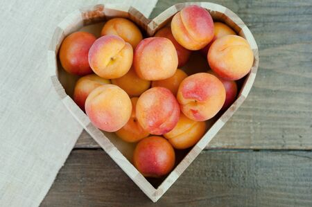 Peaches ripe fresh healthy fruit in a heart shaped bowl on a wooden backgroundの写真素材