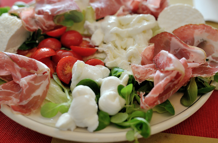 Mediterranean italian food mozzarella with tomatoes, salad and hamの写真素材