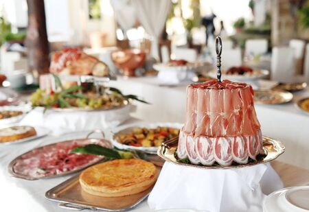 Bacon and speck slices, on background trays with sweets and cold cutsの写真素材