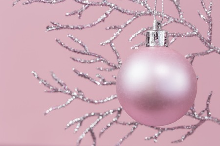 Shiny pastel pink Christmas decorations on silver branch against pink background, monochrome color with copy spaceの写真素材