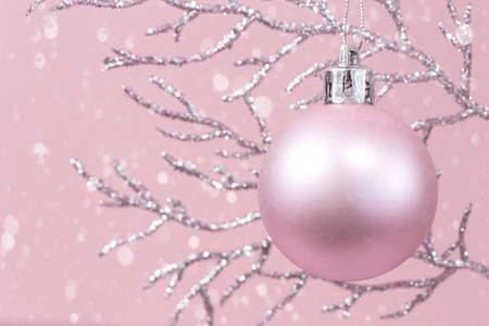 Shiny pastel pink Christmas decorations on silver branch against pink background, monochrome color with copy spaceの写真素材