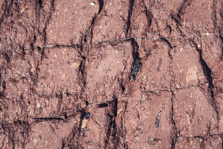 Red fractured stone surface background with deep cracks in high resolutionの写真素材