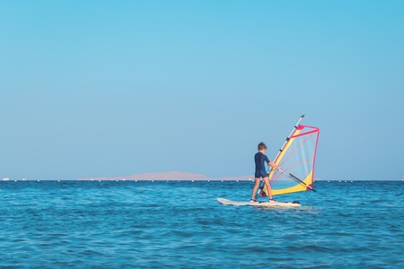 One child learning to windsurf in the sea at beautiful sunset light, close up, windsurfing passtime and school with copy spaceの写真素材