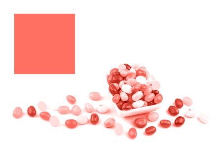 Trendy living coral color of year 2019 jelly beans in white bowl isolated