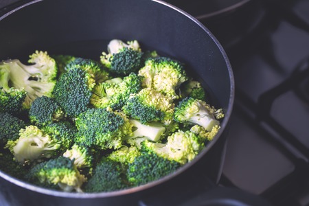 Pieces of fresh broccoli in water in a pot on stove, closeup, healthy eating or cooking conceptの写真素材