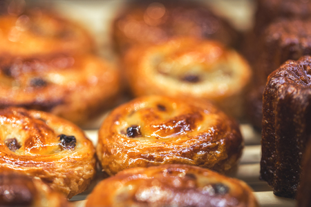 Mouthwatering Danish spiral cinnamon raisin rolls, golden and shiny on display, bakery and cafe concept, sweet indulgenceの写真素材