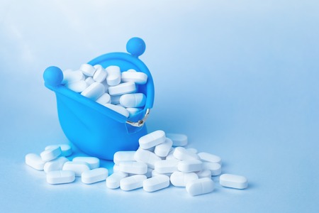 White tablets falling out of blue purse, drugs and medicine safety consumption and cost concept with copy spaceの写真素材