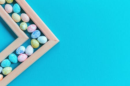 Happy Easter greeting card with small eggs in a frame, on trendy blue background. Close up with copy spaceの写真素材