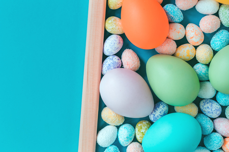 Happy Easter greeting card with assorted size eggs in a frame, on trendy blue background. Close up with copy spaceの写真素材