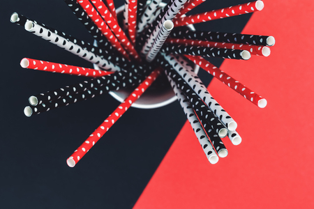 Dotted paper straws in a glass jar close up, trendy living coral red white and black party or celebration concept beyond plastic creative top view with copy spaceの写真素材