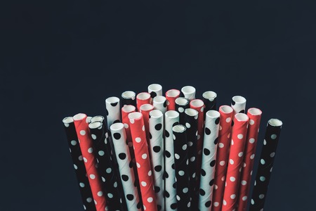 Dotted paper straws background close up, red white and black party or celebration concept beyond plastic flat lay layout with copy spaceの写真素材