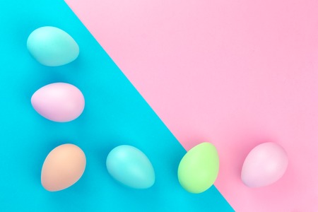 Colorful tender pastel easter eggs lined on pink and blue background in flat lay with copy spaceの写真素材