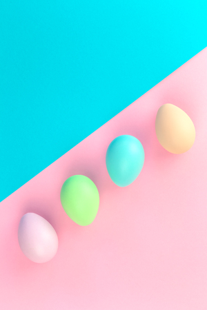 Colorful pastel easter eggs lined on pink and blue background in flat lay with copy spaceの写真素材