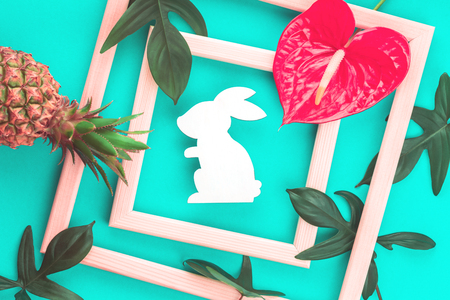 Happy Easter greeting card with pastel eggs and leaves in a frame, on trendy mint background with Easter bunny. Close up with copy spaceの写真素材