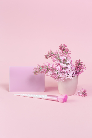 Feminine accessories with unicorn makeup brushes on pink background and trendy lilac branch with a card. copy space, birthday beauty and cosmetics blogger conceptの写真素材