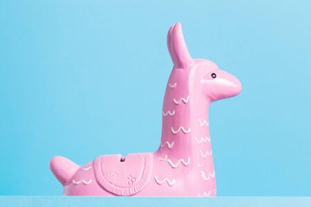 Pink funny zine type head of a cute toy lama on a blue background close up. Creative and fun trendy...