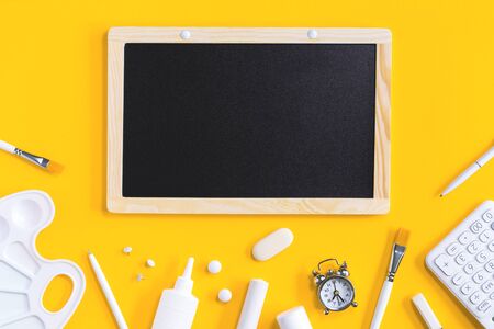 Assorted office and school white stationery on bright yellow background with black board. Flat lay with copy space for back to school or education and craft conceptの写真素材