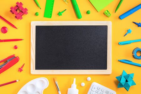 Assorted office and school red green blue and white stationery on bright yellow background with...