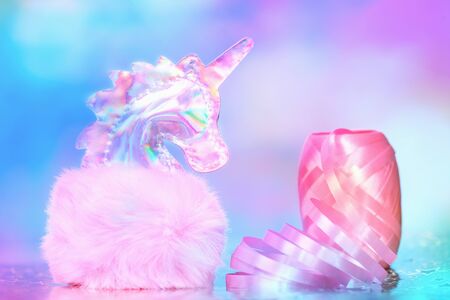 Shiny zine type gradient holographic iridescent head of pink soft fluffy toy unicorn on bright blue pink bokeh fluorescent neon background. Celebration birthday greeting card concept with copy spaceの写真素材