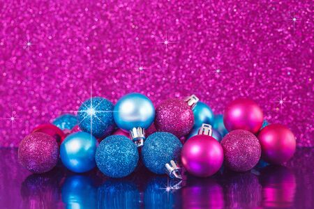 Christmas blue and pink shiny baubles collection with sparks on festive pink glitter background. Merry Christmas or Happy new year card concept in rich colors with copy spaceの写真素材
