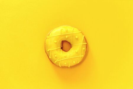 One tasty fresh Donut with yellow glaze centered on matching yellow background. Top view flat lay with copy spaceの写真素材