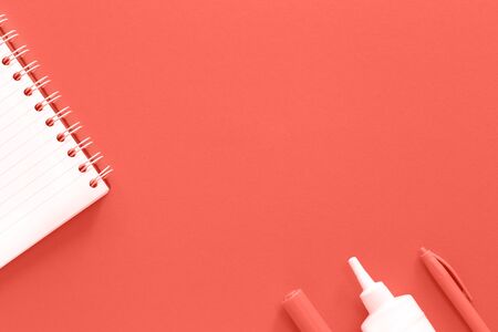 Trendy monochromatic white and living coral color stationery and notepad flat lay with copy space background. Minimalistic school or office conceptの写真素材