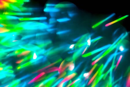 Multicolor neon lights flares and trails lines in motion on isolated black background. Bokeh lens flare glow. Festive backdropの写真素材