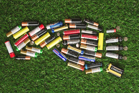 Minsk, Belarus August 2019. Footprint of used alcaline batteries on green grass. Toxic waste management and recycling. Damage to environmentのeditorial素材