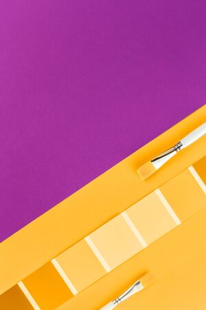 Trendy yellow orange color swatches with grape pink background and paint brushes. Color palette creativity crafts and design conceptの写真素材