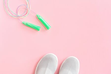 Lightweight modern textile grey slip on sneakers shoes with skipping jumping rope on pastel pink background in flat lay with copy space. Weight management and healthy lifestyle sport conceptの写真素材