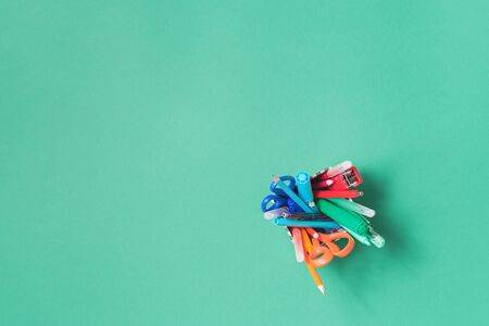 Assorted office or school multicolored rainbow stationery on pastel green background. Flat lay top...