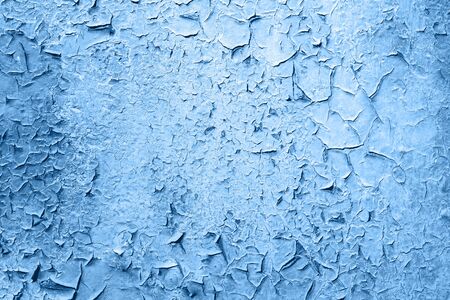 Old grungy cracked blue weathered wall paint peeling off rusted metal sheet. Textured background for...