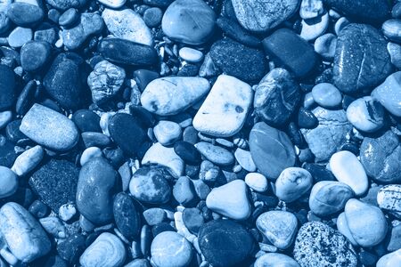 Wet pebble stones and sea water in beautiful morning light. Monochrome blue color. Closeup, travel...