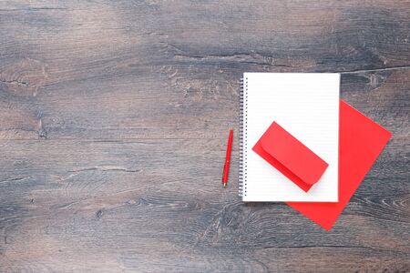 Blank notepad with red office supplies and red envelope on wooden desk table. Flat lay with copy space office or school education blogger or test conceptの写真素材