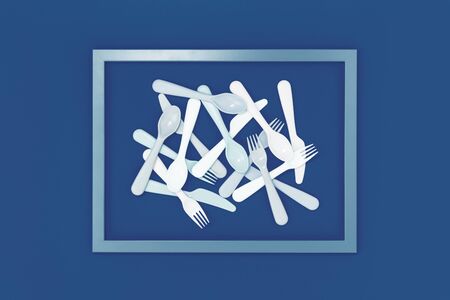 Scattered white reusable plastic cutlery framed on trending blue color background. Eco friendly zero waste concept flat lay. Informed choiceの写真素材