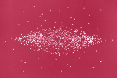 Red scattered holographic glitter confetti star shaped on blue background. Flat lay top view copy...