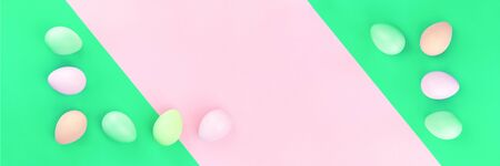 Happy Easter banner of tender dyed pastel easter eggs lined on pink and green background in flat lay with copy spaceの写真素材