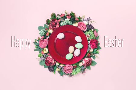 Several pastel Easter eggs on large red plate with rich roses and peony floral wreath in subtle...