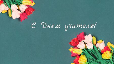 Bouquet of fresh tulips on dark teal emerald background like school chalk board. Flat lay with copy space. World happy Teachers Day celebration greeting card in Russian language or minimal bannerの写真素材