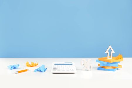Business or education growth development and success concept banner. White calculator with percentage sign and an arrow on desk. blue background. Copy space. Startup concept innovative investmentの写真素材