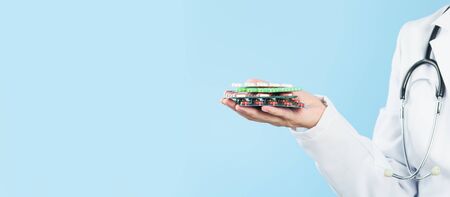 Hand of female doctor holds several pills or tablets blister packs. Medicine and pharmacy, prescription drugs or vitamins concept. Copy space bannerの写真素材