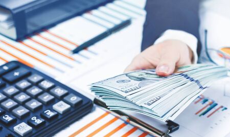 Finance and business concept. small business growth. Hand holding cash dollars stack over financial...