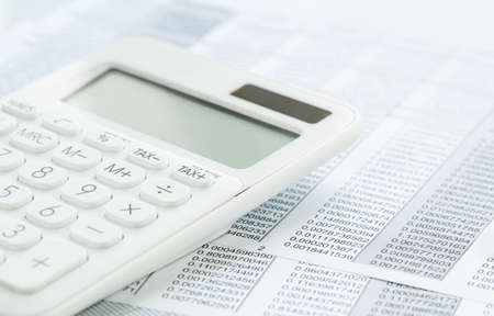Finance and business concept. White calculator on financial graphs on office desk, spreadsheet. Accounting budgeting or market analysis. Web banner with copy space. Minimal monochromeの写真素材