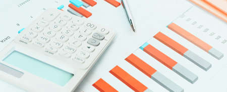Finance and business concept. White calculator on financial graphs on office desk, paperwork folders. Accounting budgeting or market analysis. Web banner. Minimal monochromeの写真素材