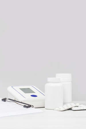 Medicine and pharmacy background. Pills and blood pressure monitor against monochrome grey...