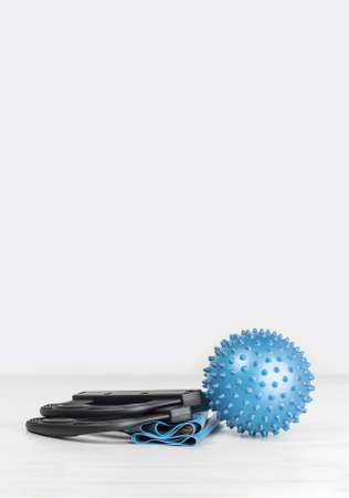 Blue sports equipment. exercise resistance band and massage ball on grey wooden surface. Gender neutral fitness exercise concept with copy space. Active lifestyle and sport. Workout at home or gymの写真素材