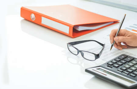 Finance and business. Financial office space with graphs. Paperwork binder and calculator, hand of a...