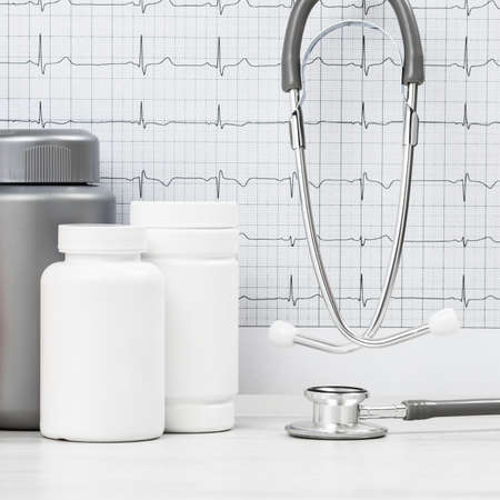 Medicine and pharmacy background. Pills and stethoscope against ECG with printed heart rate. Medical...