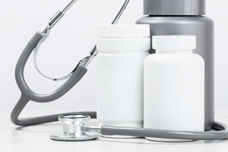 Medicine and pharmacy background. Pills and stethoscope monochrome grey background. Mockup white vials. Medical concept. Copy space.の写真素材
