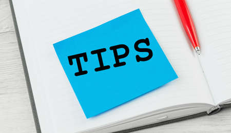 Tips word on a notebook with red pen. Top tips or quick advice conceptの写真素材